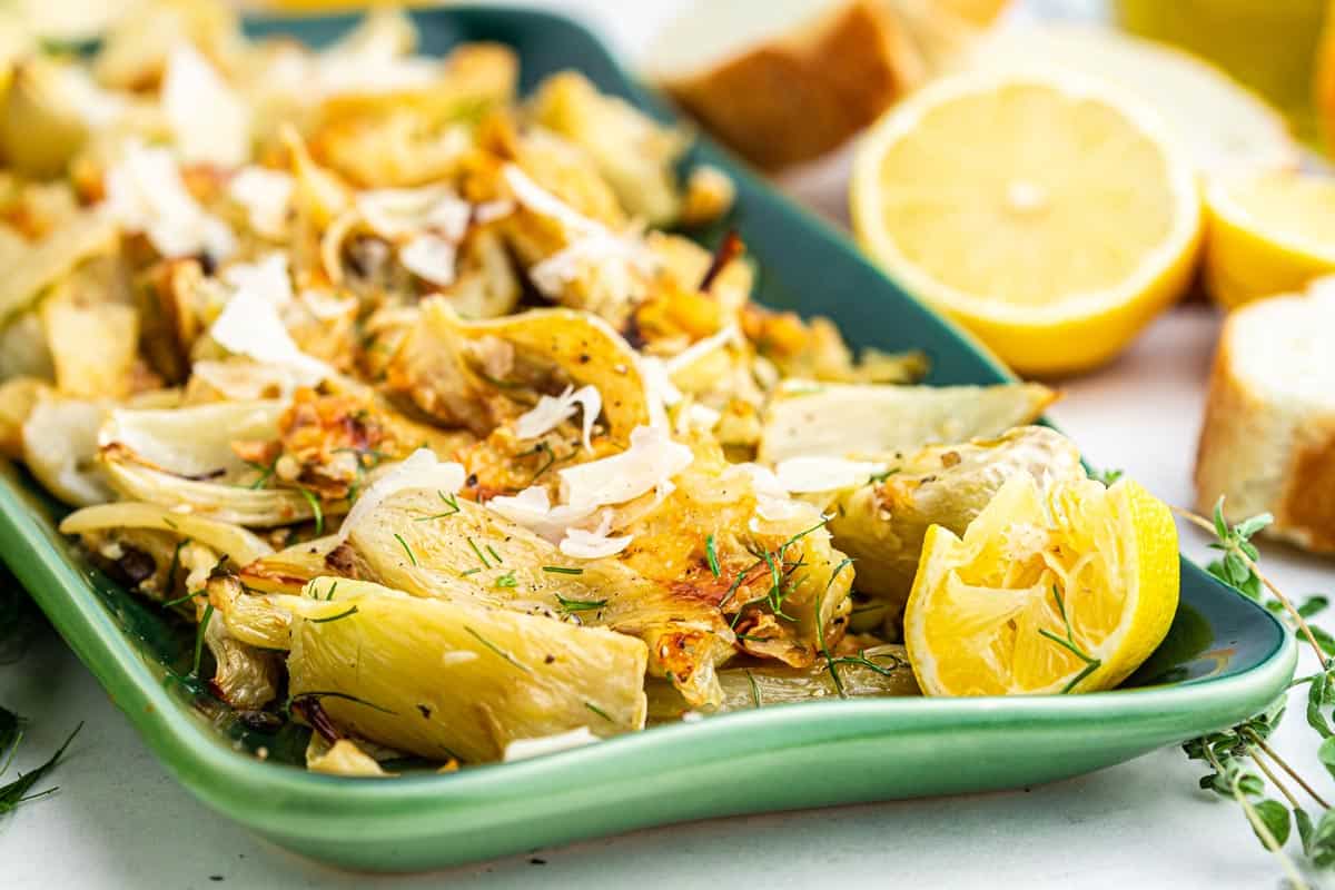 Tray of roasted fennel with lemon garnish