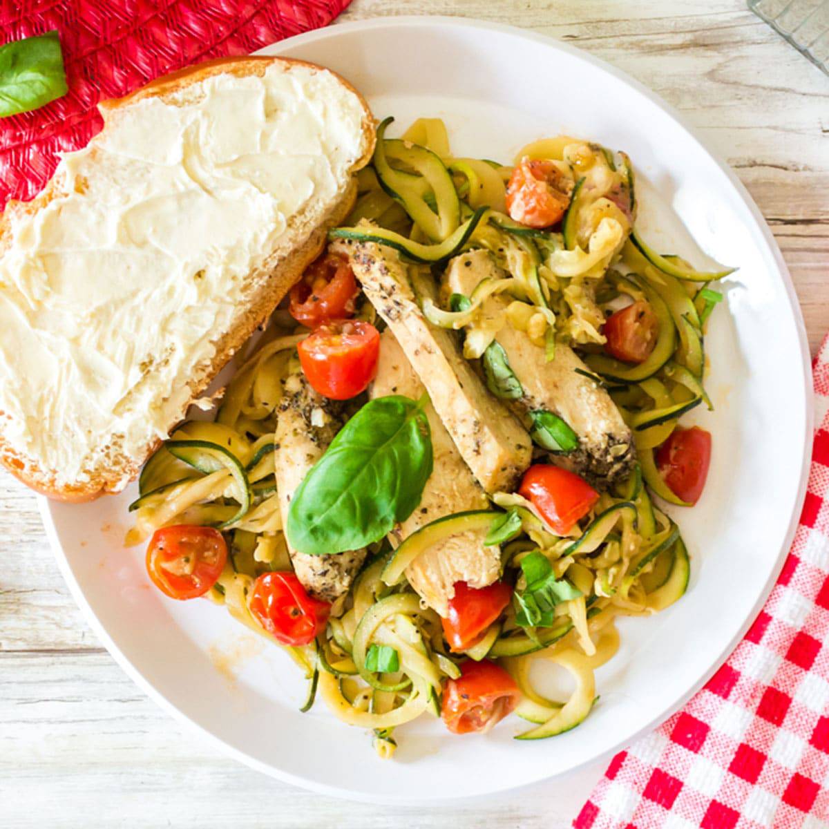 Plate of zucchini noodles with a slice of bread.