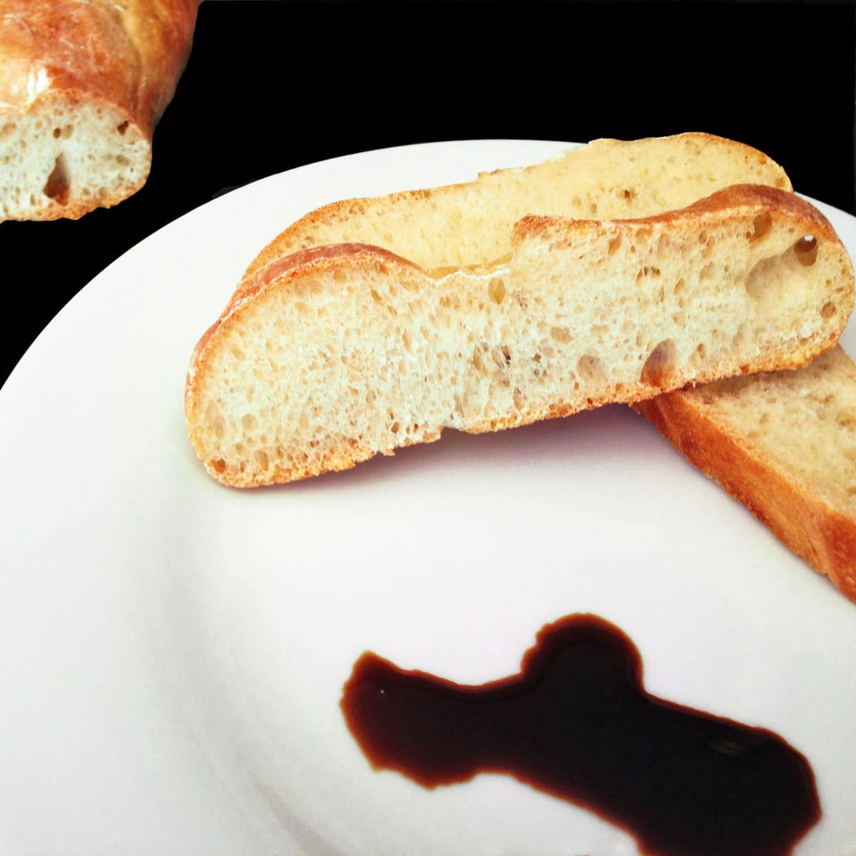 Sliced ciabatta bread on plate with balsamic vinegar