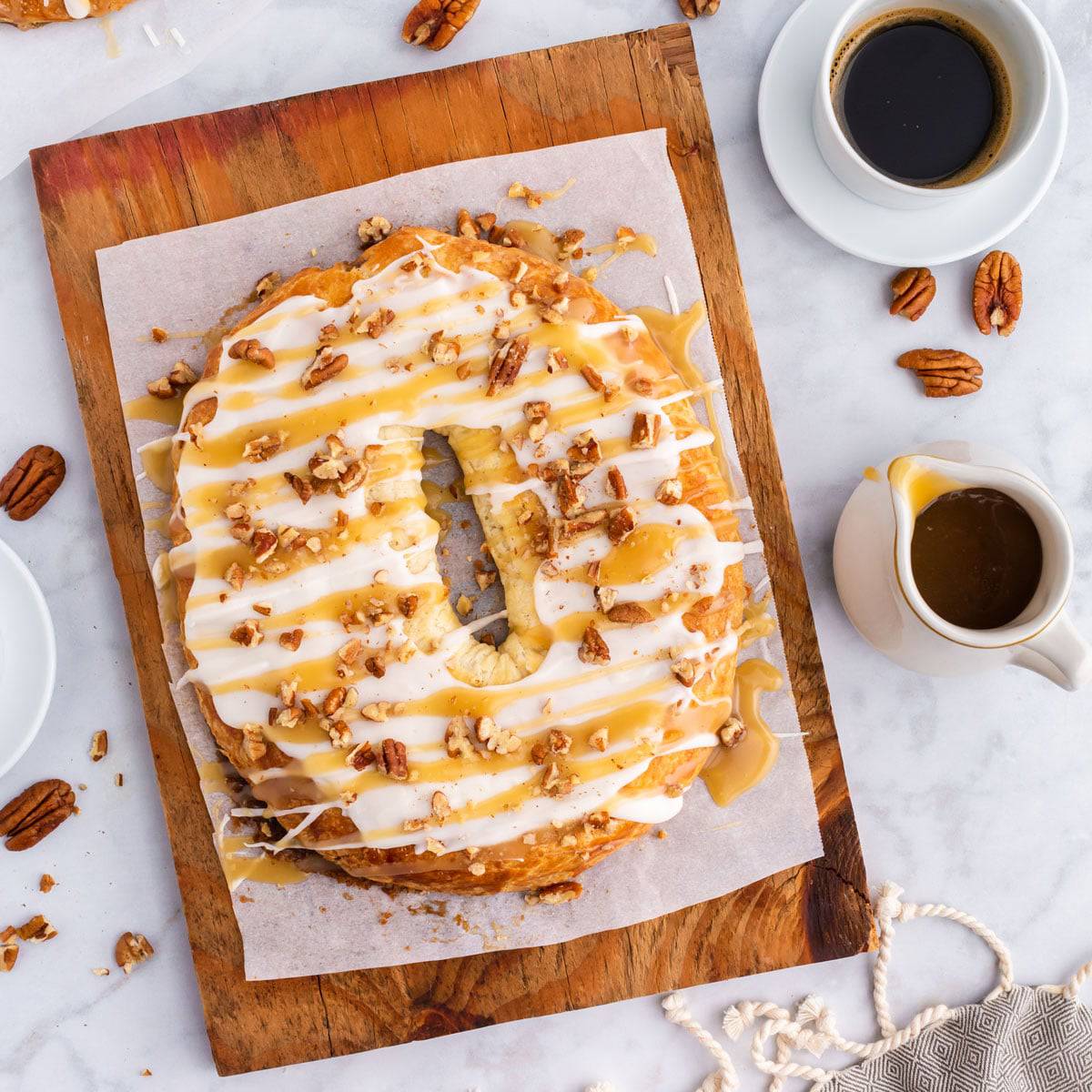 A homemade pecan-filled kringle. An oval-shaped pastry on a cutting board
