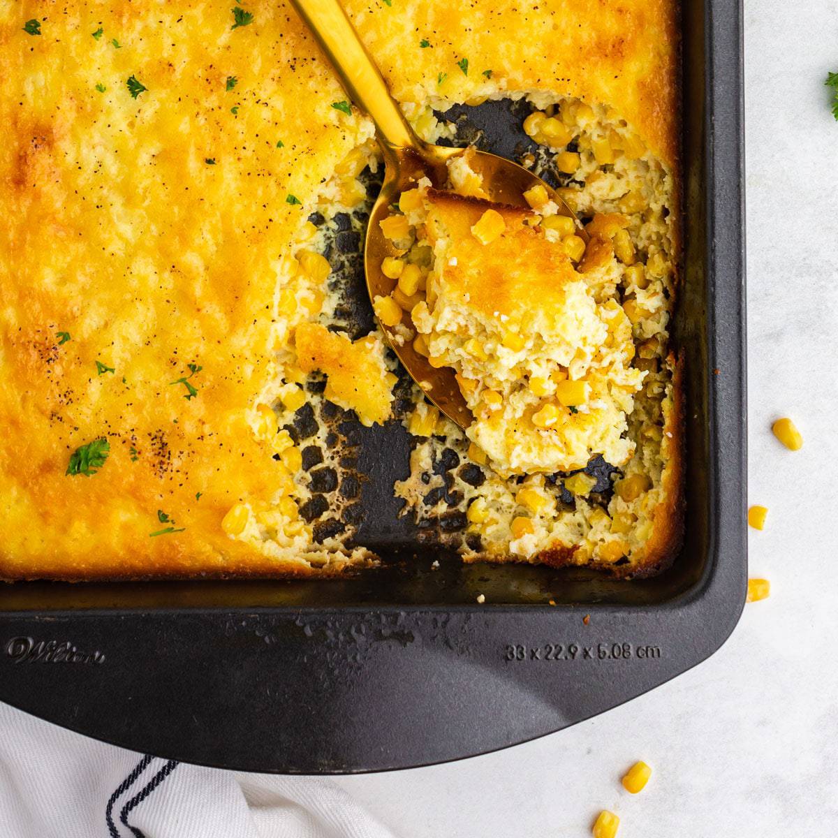 A pan of corn pudding with a spoon