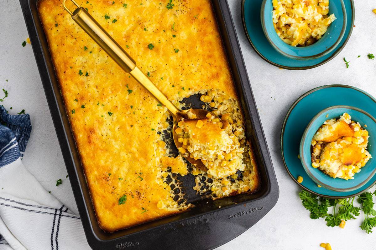 A pan of corn casserole with two bowls
