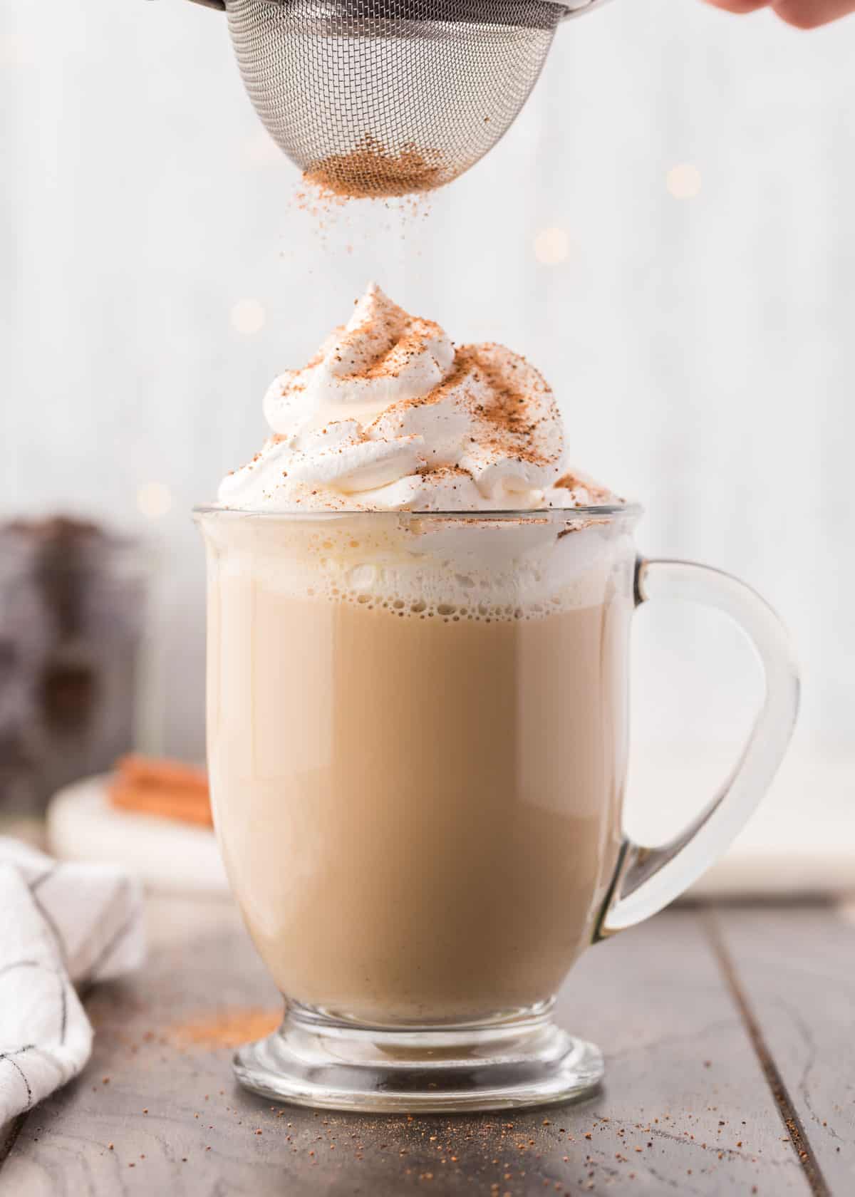 Sprinkling cinnamon on top of an eggnog latte