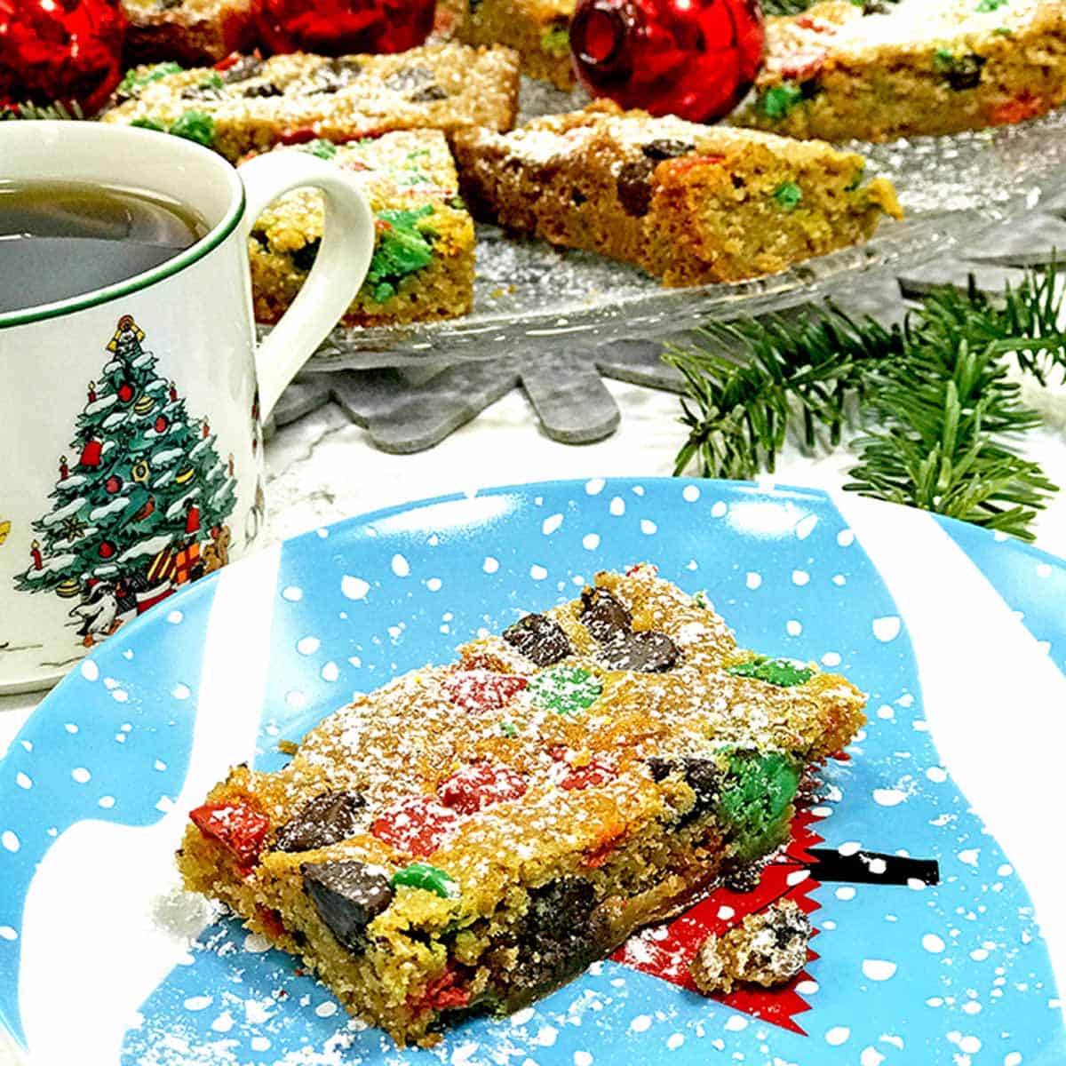A Christmas bar cookie on a plate with a cup of coffee.
