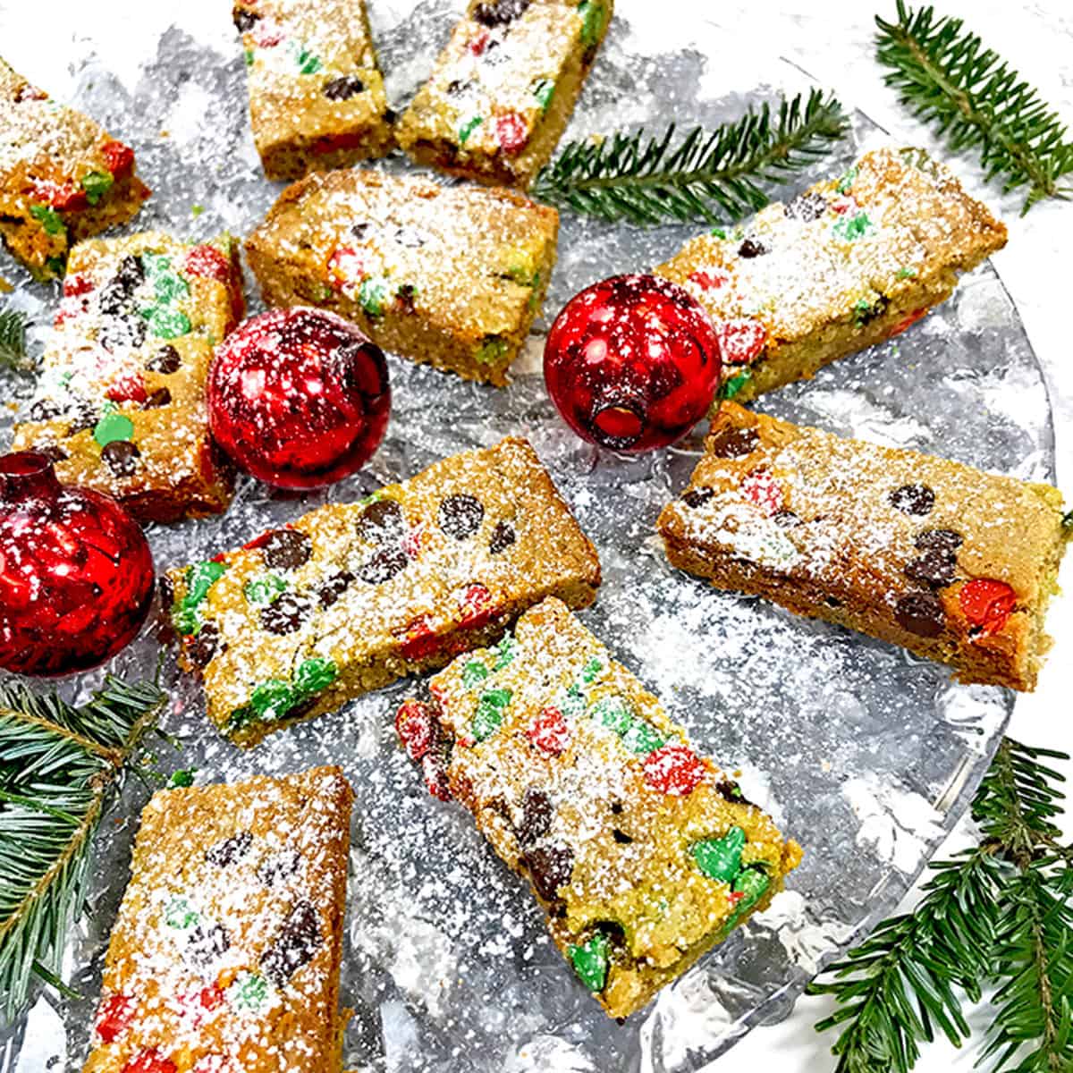 A festive plate of Christmas cookie bars with red ornaments.