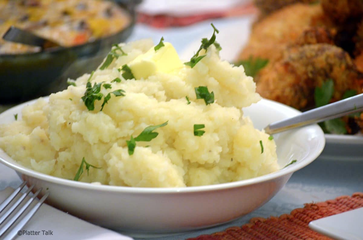garlic mashed potatoes. Closeup of bowl of mashed potatoes garnished with parsley.