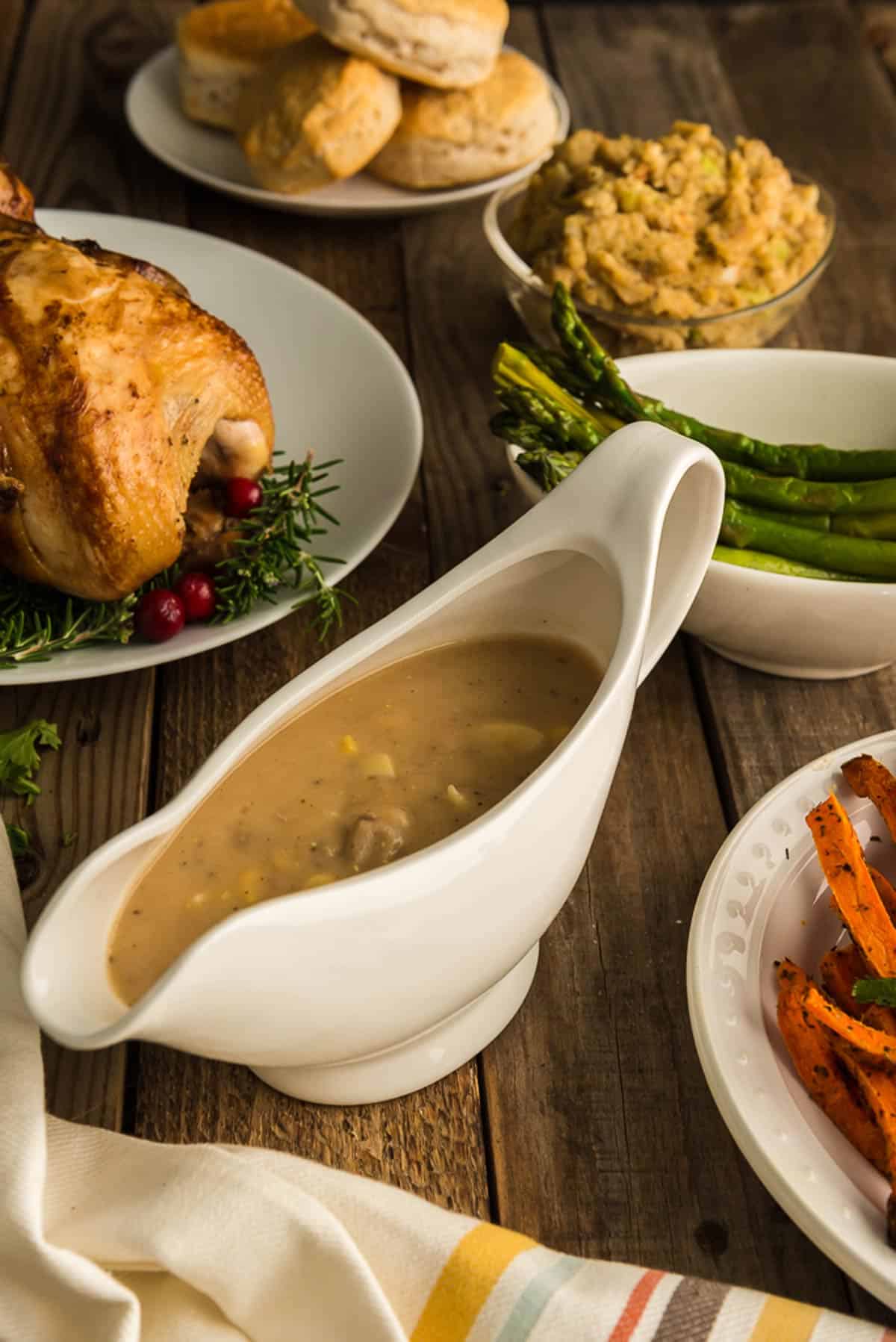 A serving dish of giblet gravy and other holiday food on a table.