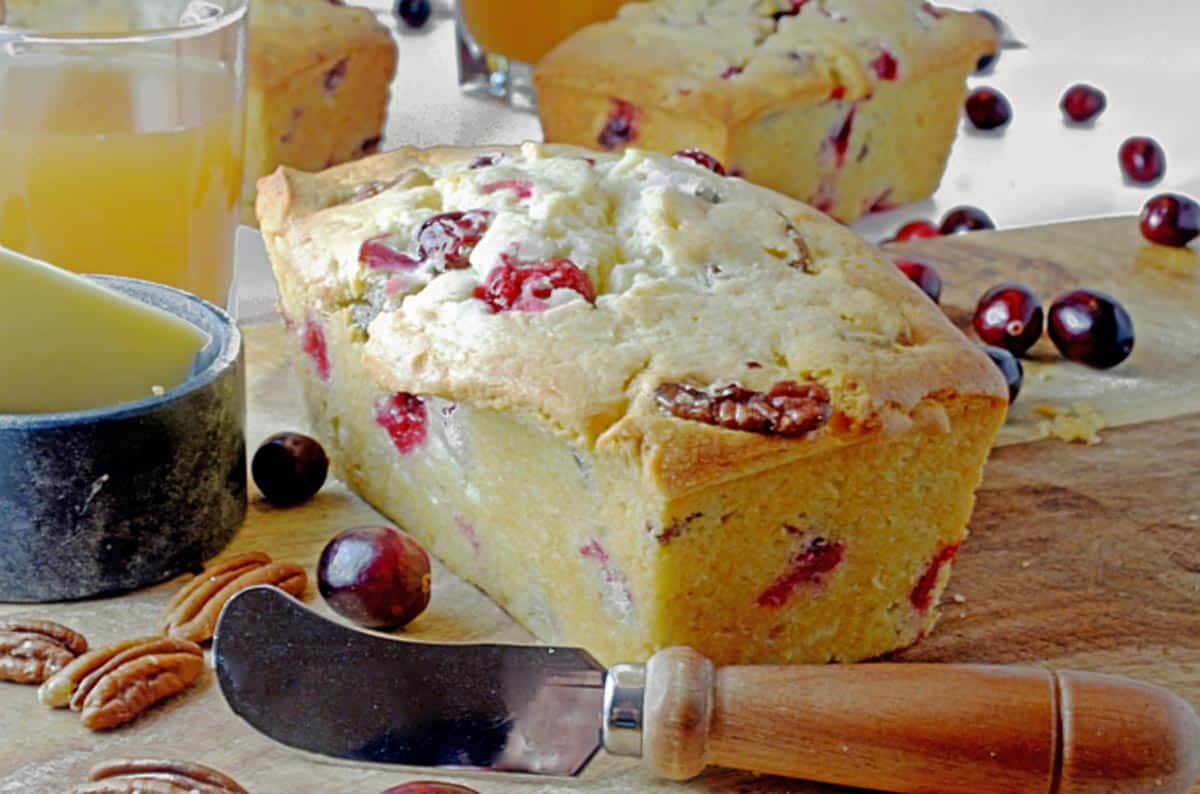 A loaf of cranberry nut bread on a cutting board.