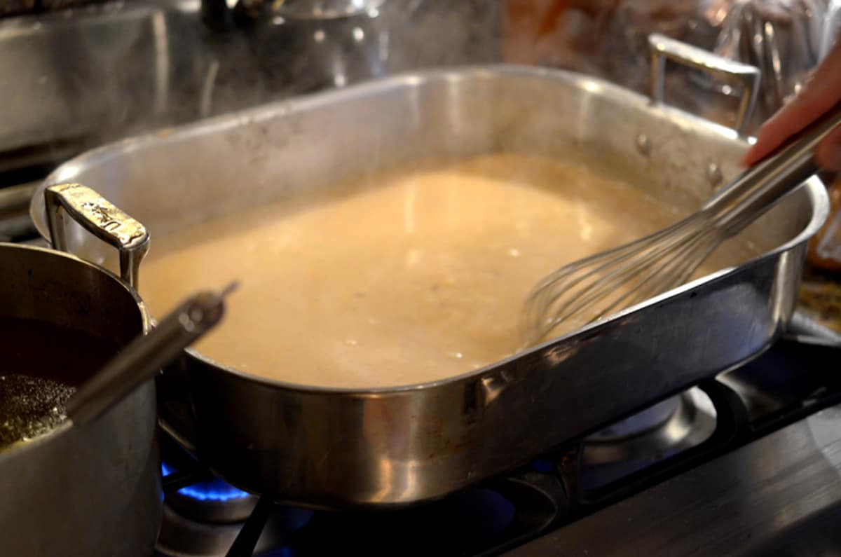 Making gravy using a roasting pan on a stove top.