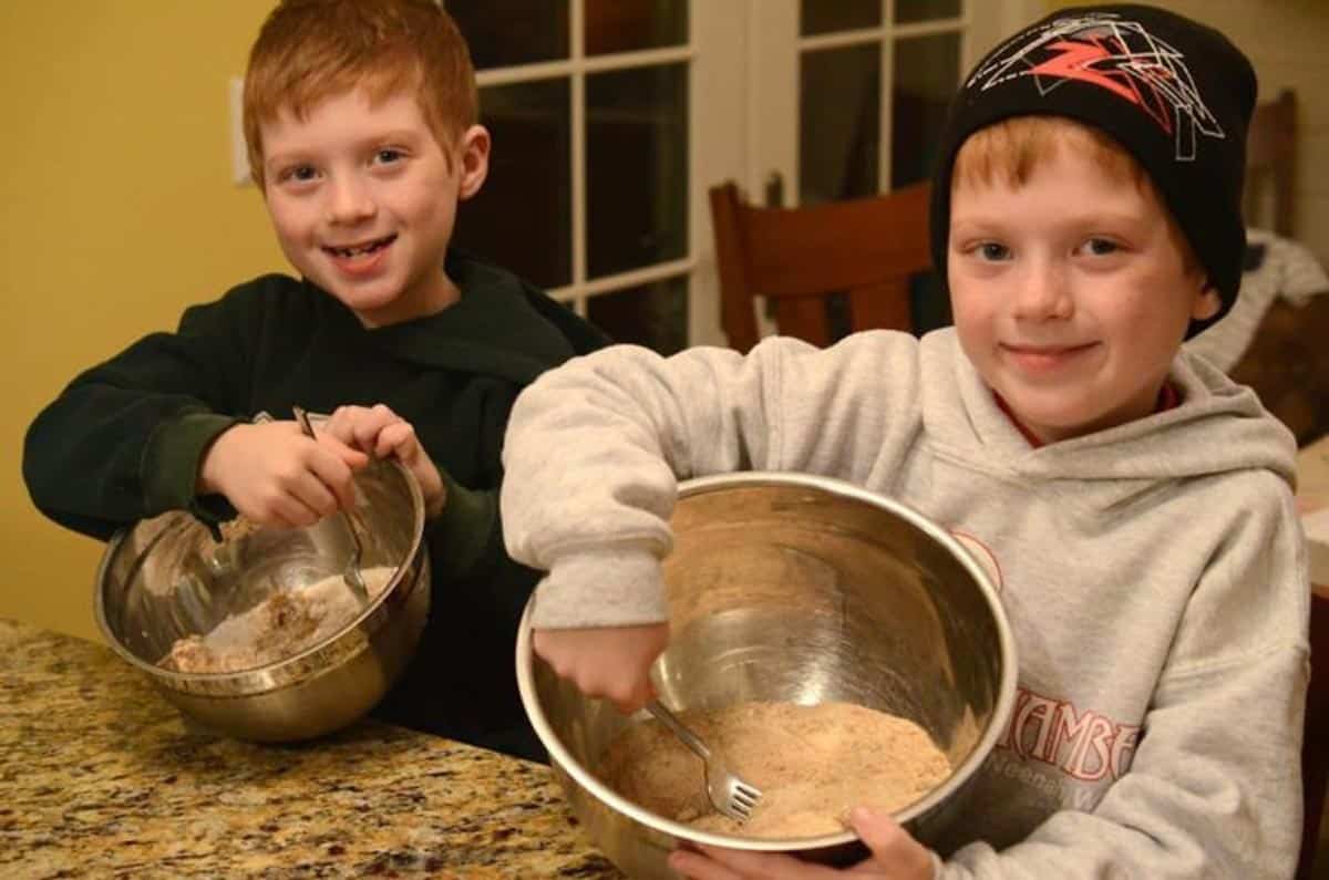 Two young boys mixing pie ingredients in mixing bowls.