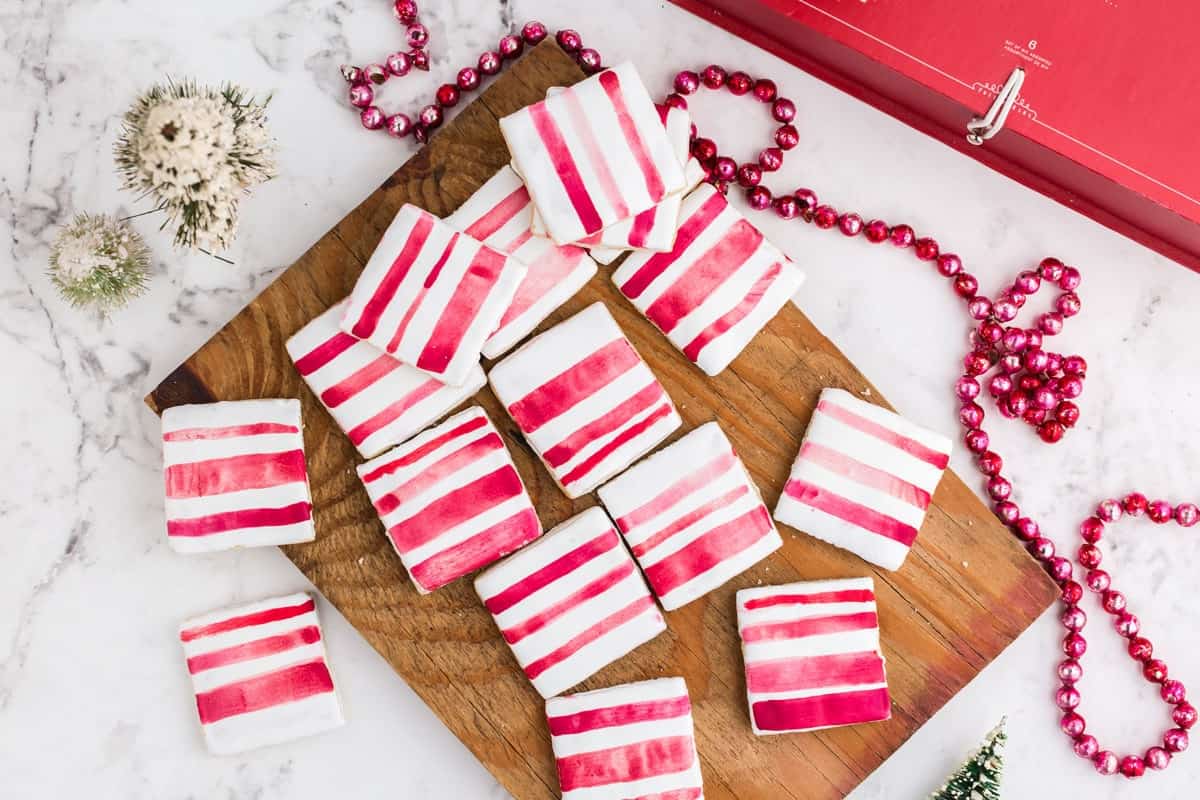 A bunch of square peppermint sugar cookies on a cutting board 