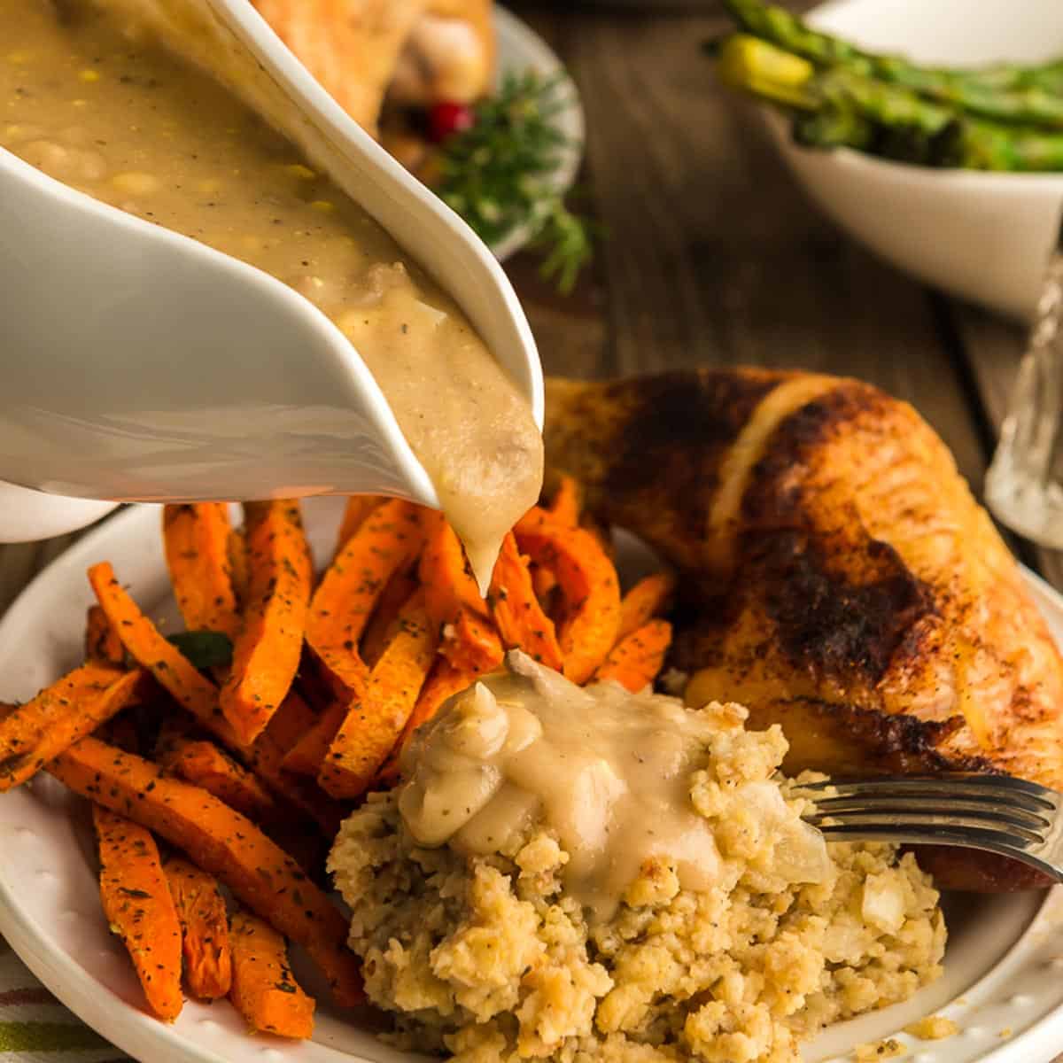 Pouring giblet gravy onto dressing and a plate of food.