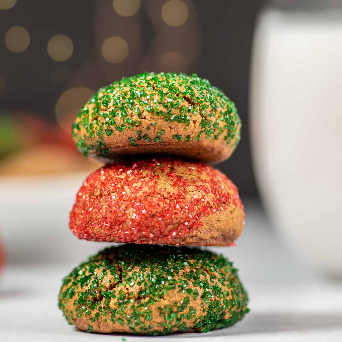 a stack of colored crinkle cookies with a glass of milk