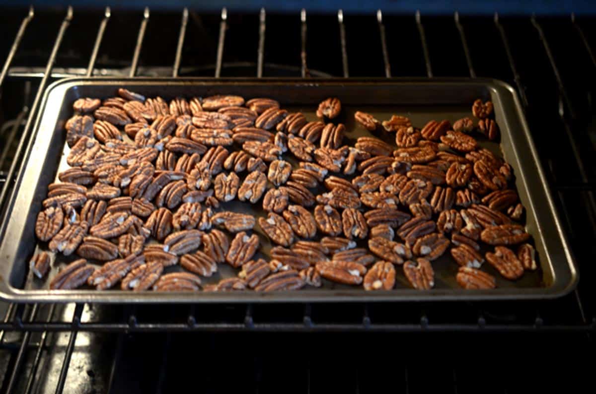 A sheet pan of pecans toasting in the oven.