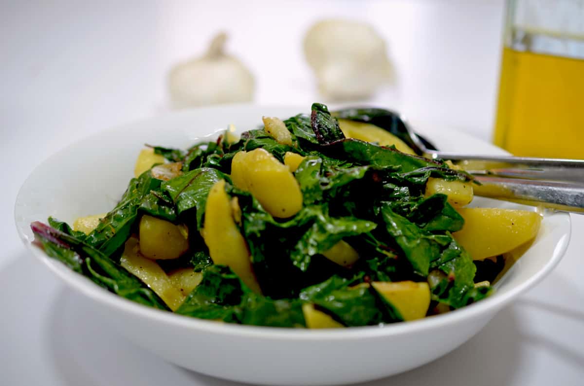 A serving dish of blitva with garlic and olive oil in the background.