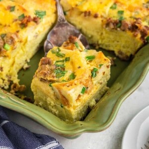 Cuttting a portion of breakfast casserole in a green baking pan.