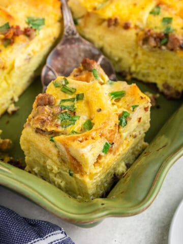 Cuttting a portion of breakfast casserole in a green baking pan.