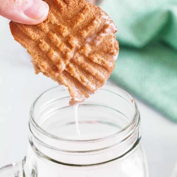 A cooking being dunked in a glass of milk.