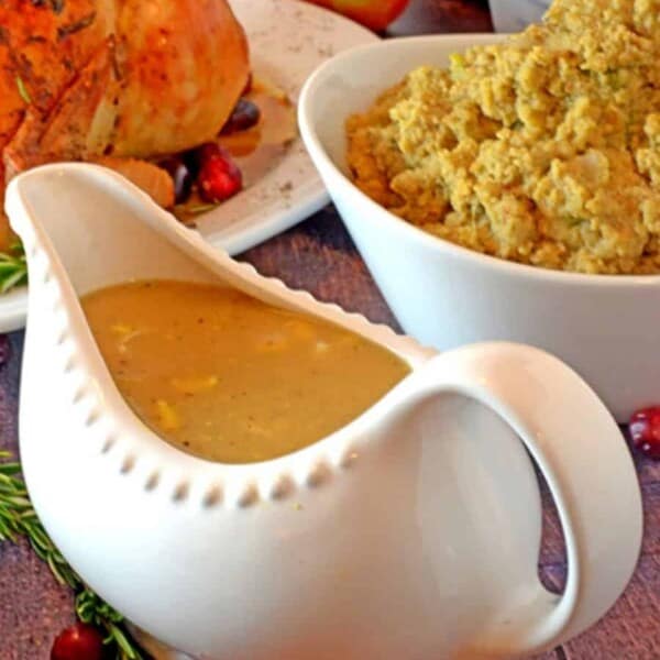 A gravy boat of giblet gravy with dressing and roast chicken.