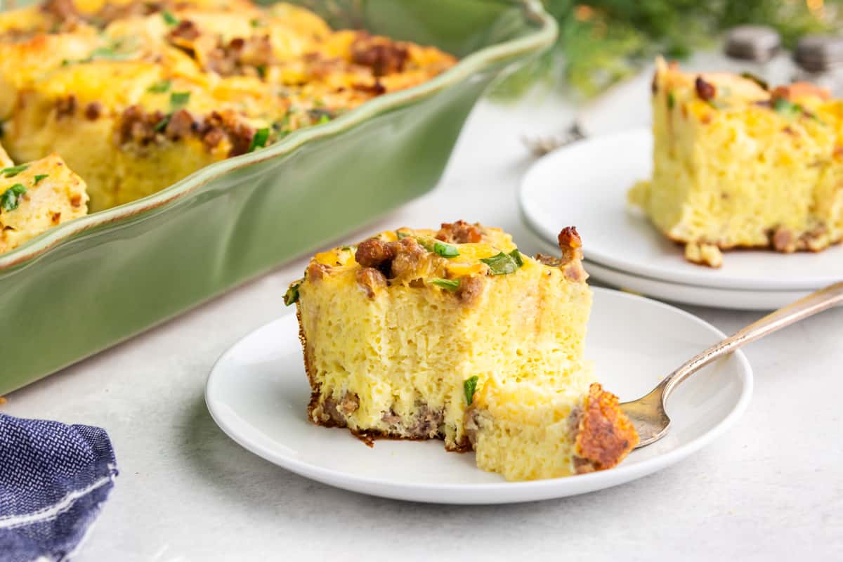 A serving of overnight breakfast casserole. A plate of egg and sausage casserole.