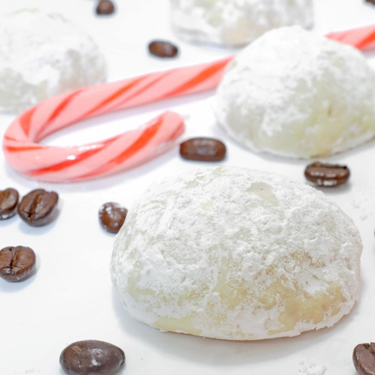 A plate of snowball Christmas cookies with a candy cane.