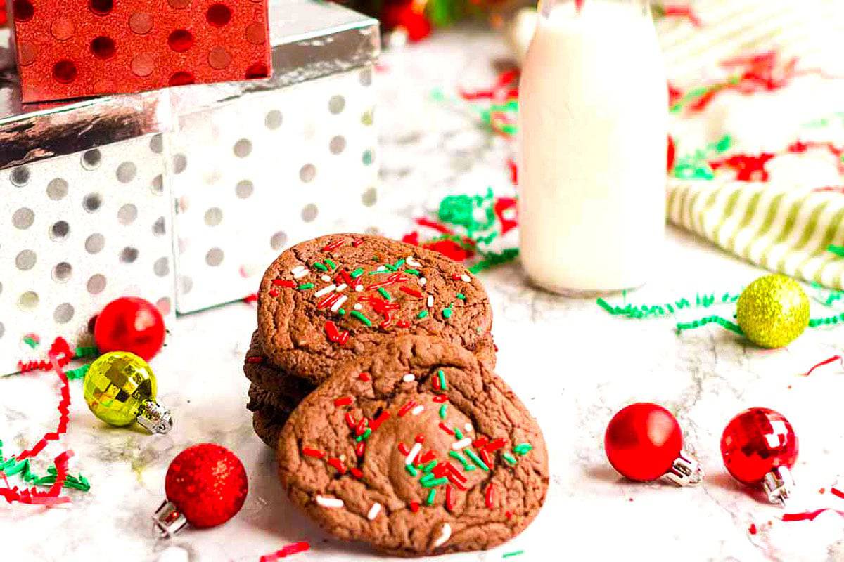 Some chocolate cookies with Christmas ornaments and a bottle of milk.