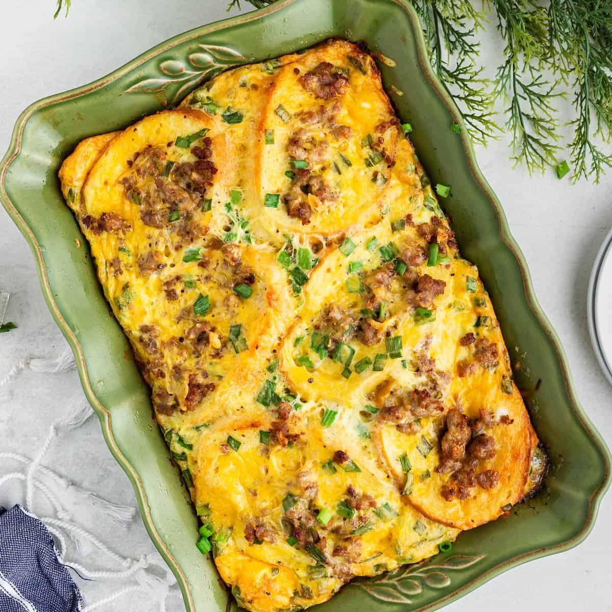 Christmas breakfast casserole read to eat. Overhead view of a breakfast casserole in a green baking dish.