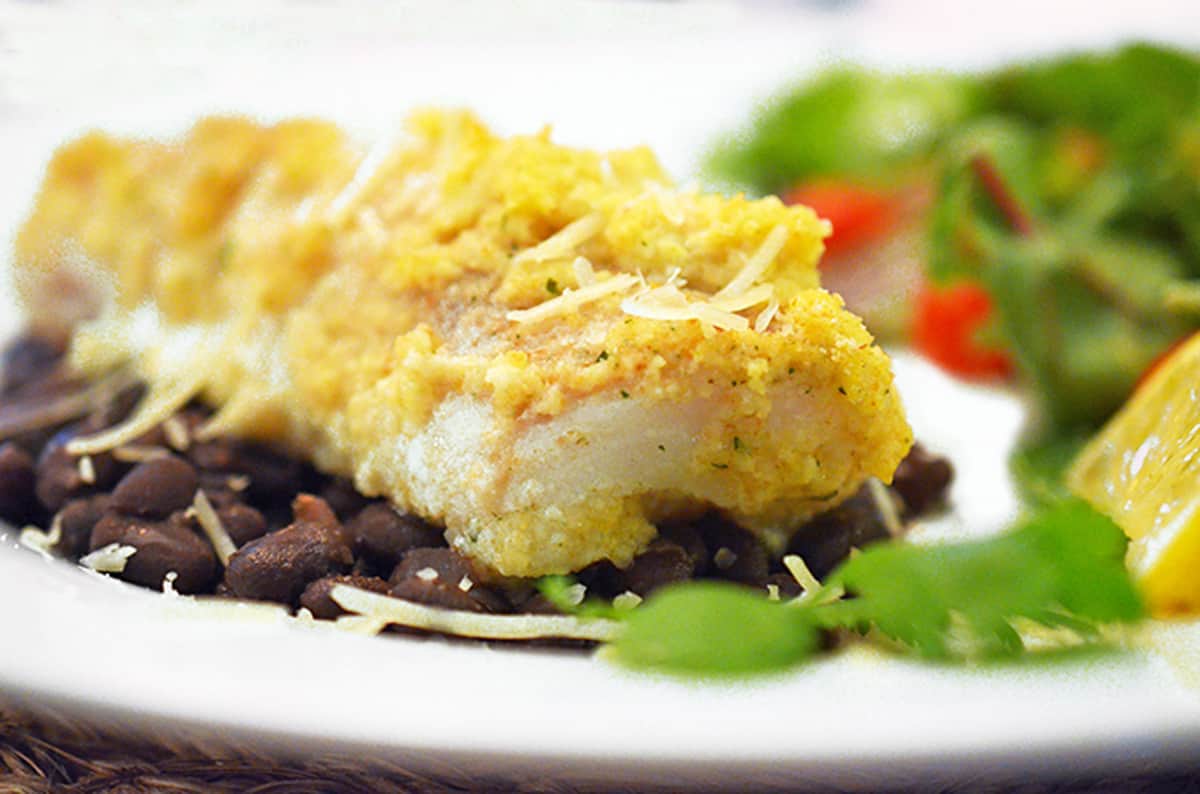 A plate of baked whitefish over black beans.