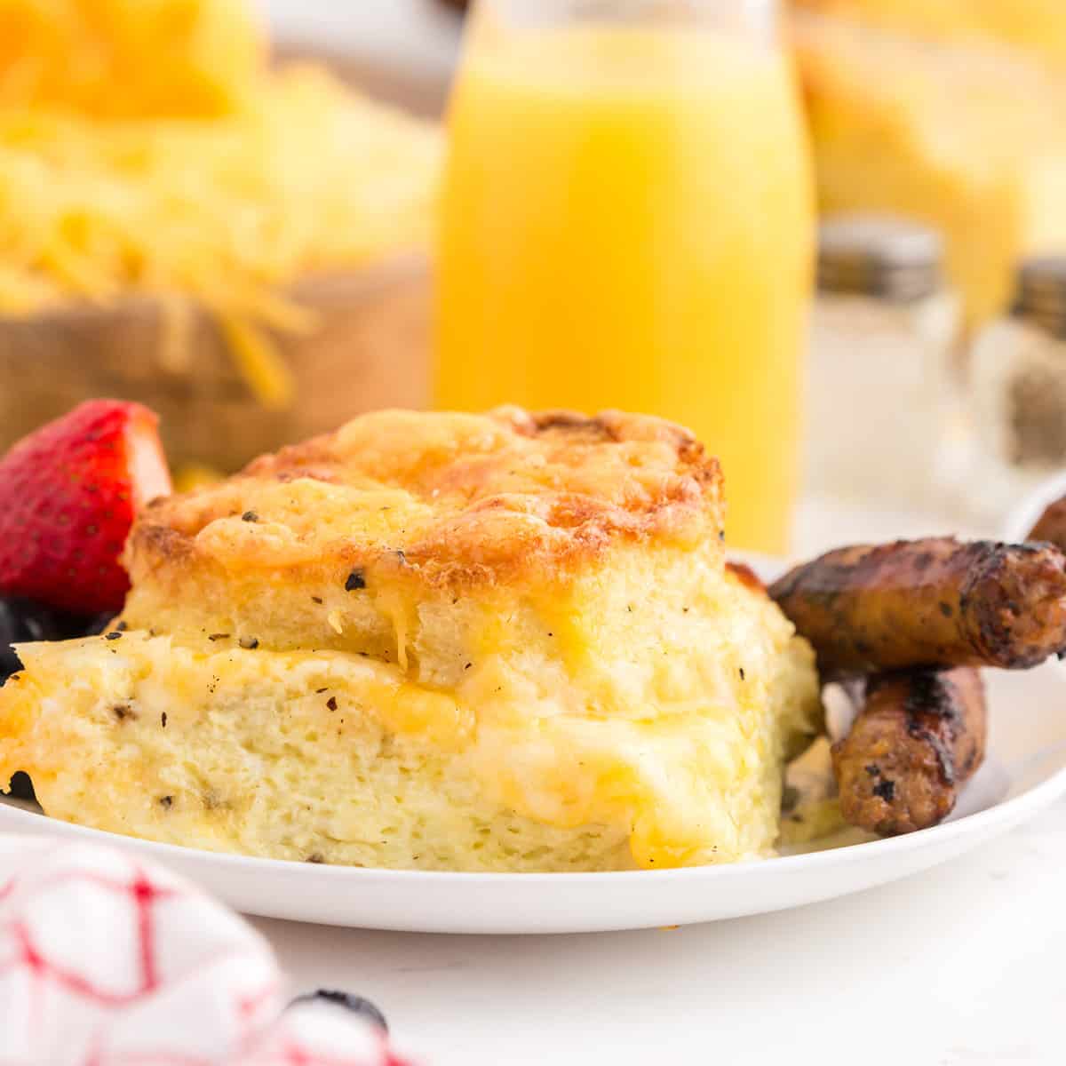 A serving of cheese strata on a plate with sausage.