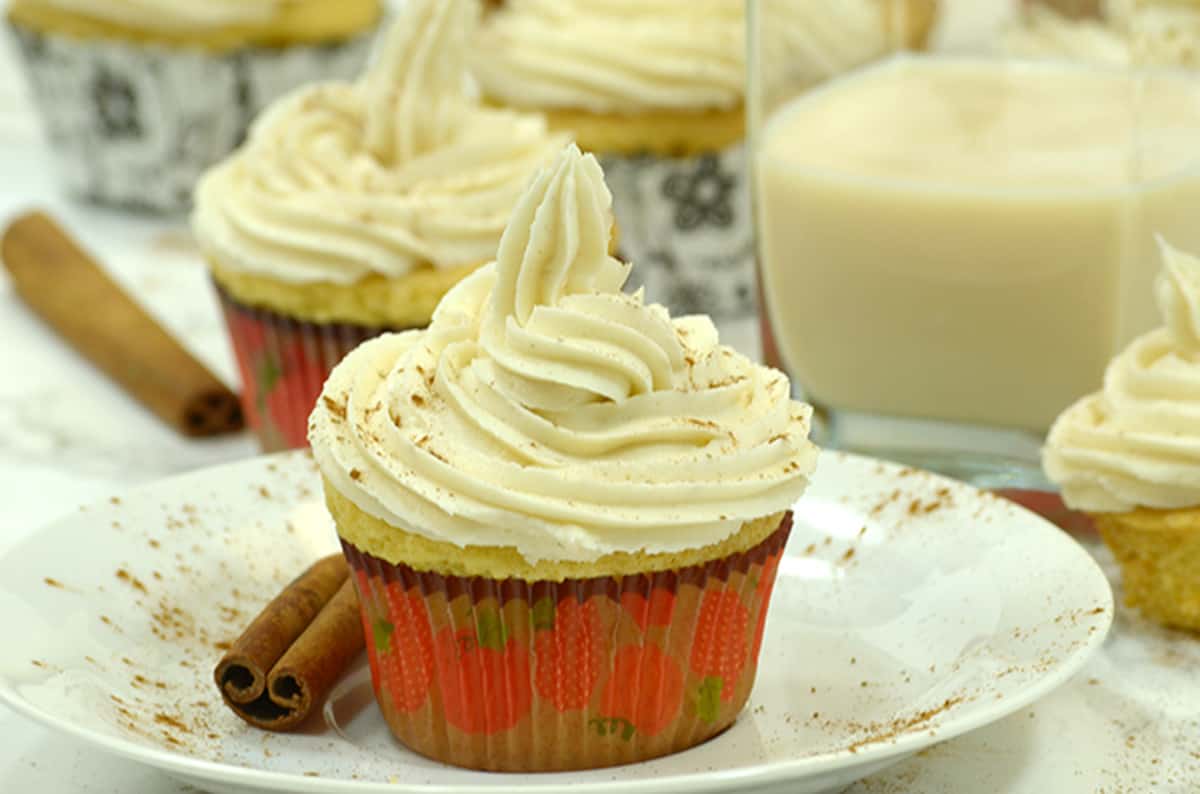 A bunch of cupcakes on a plate and some cinnamon sticks.