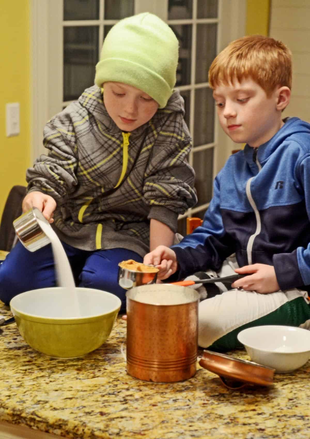 2 young boys mixing ingredients for a cookie recipe.