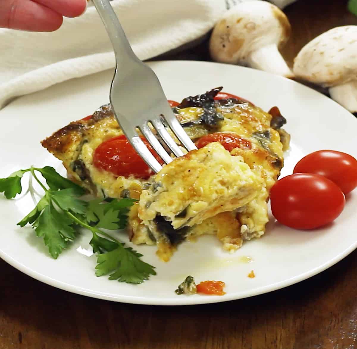 A plate of vegetable quiche on a white plate.