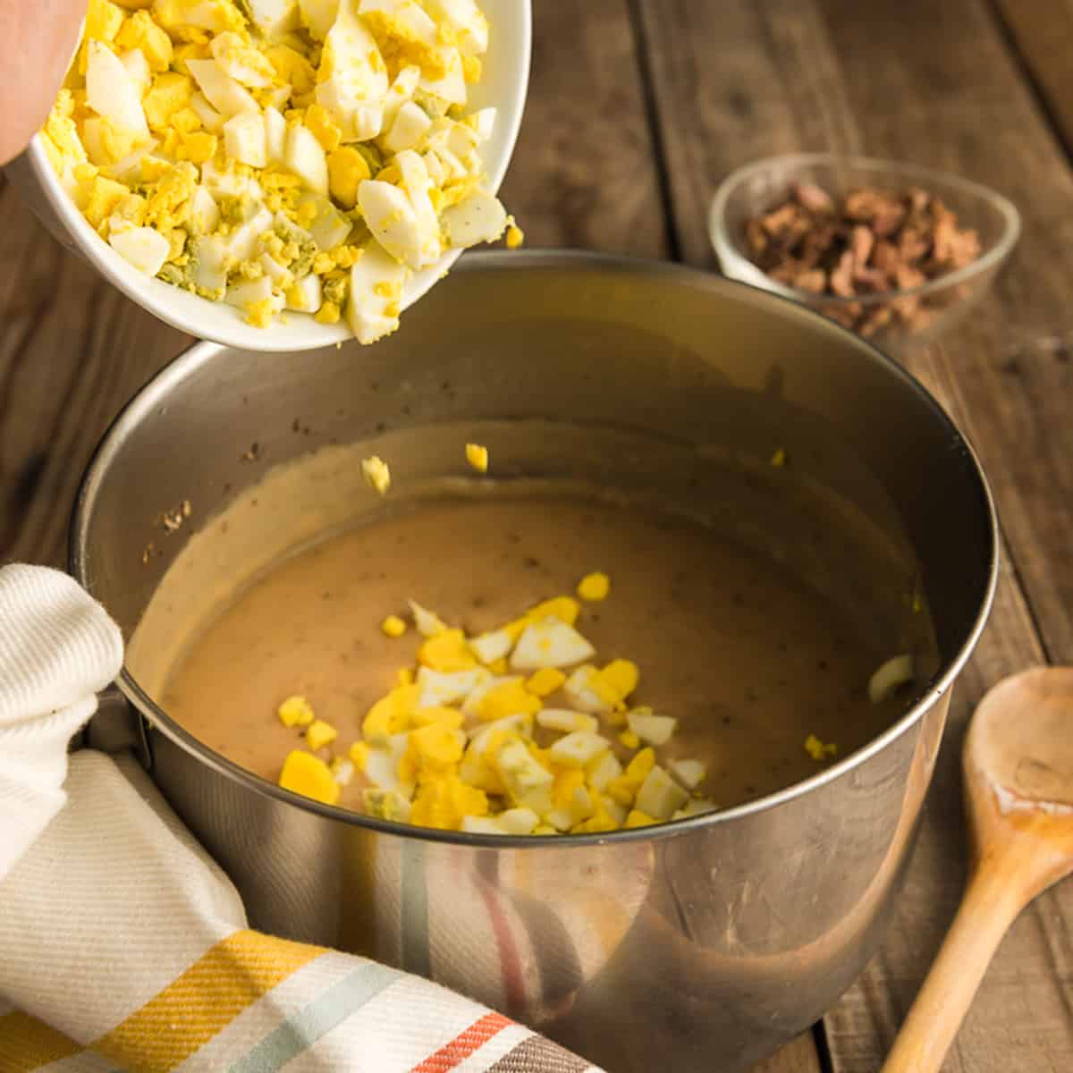 Adding chopped hard boiled eggs to a pot of gravy.