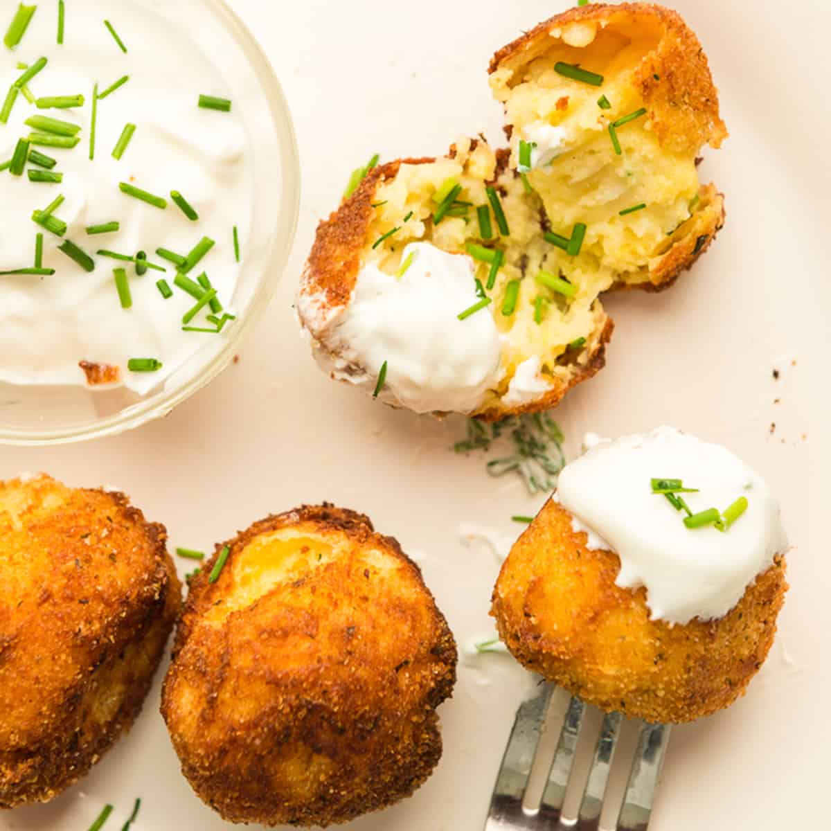 A plate of potato croquettes with sour cream.