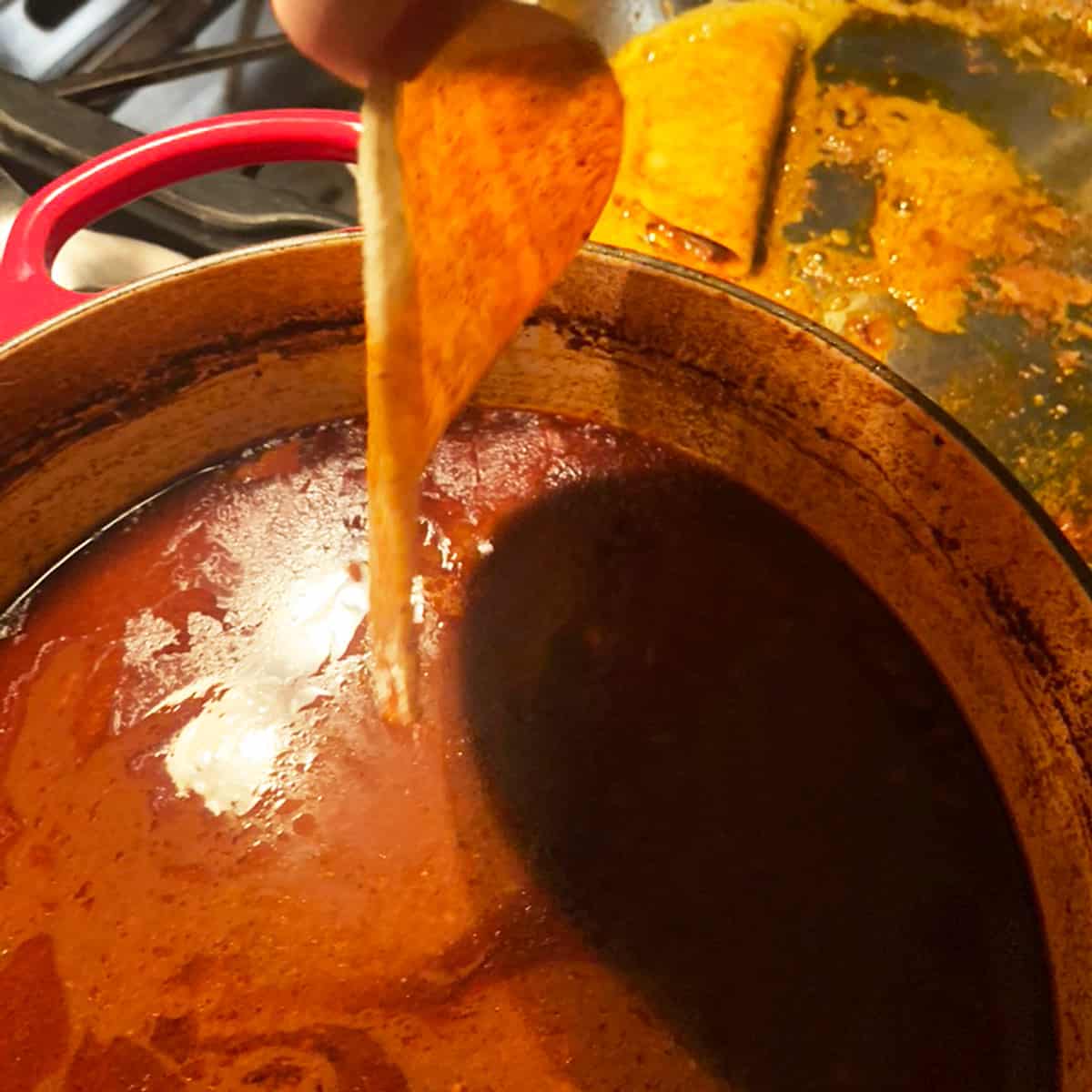 Dipping a tortilla shell in sauce.