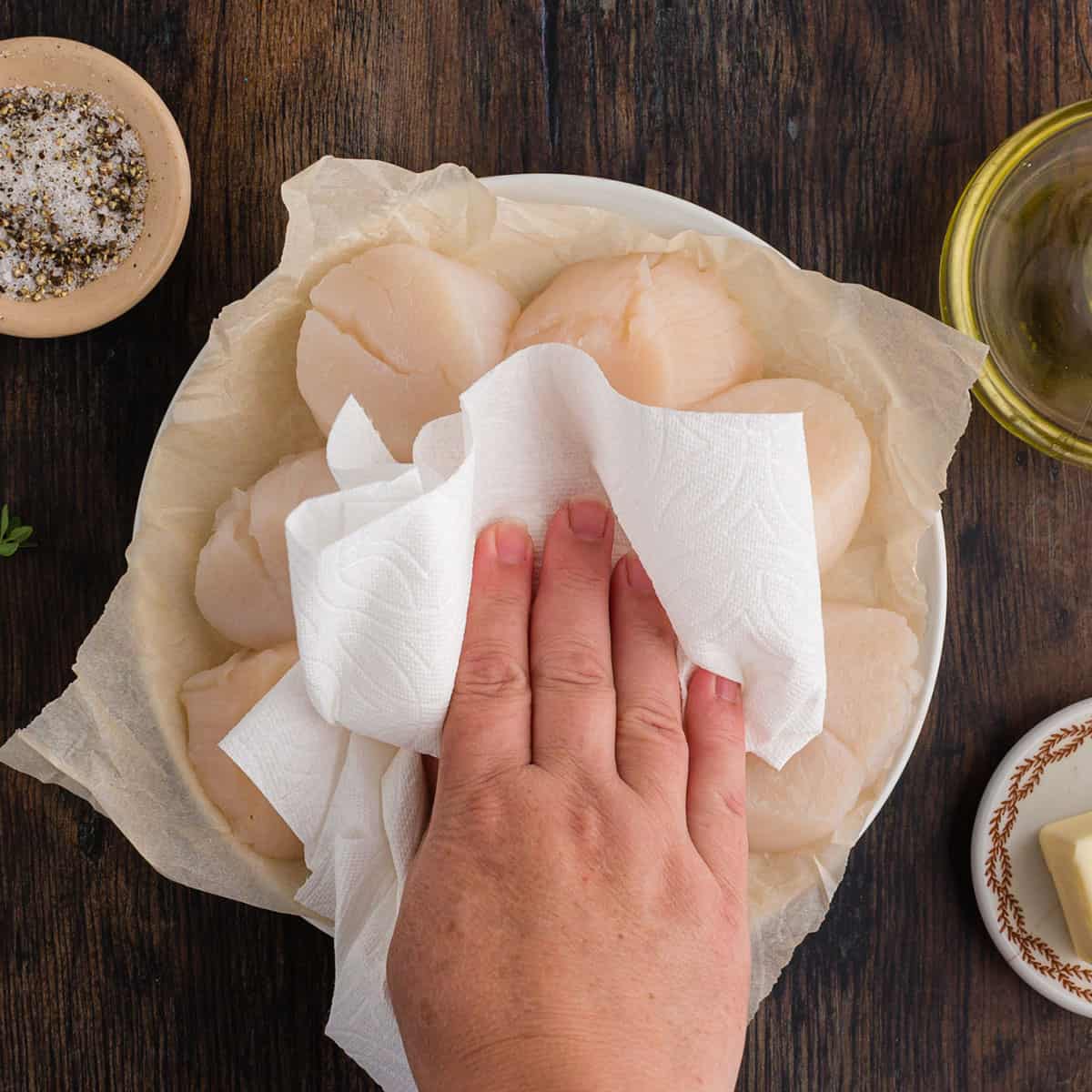 Blotting scallops dry with a paper towel.