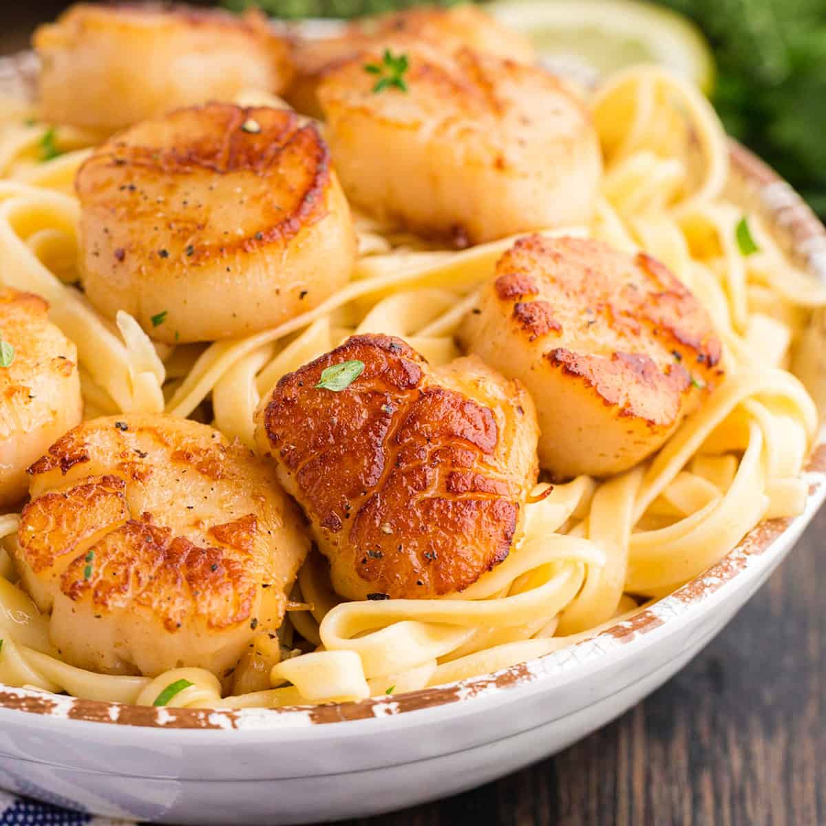 Alton Brown Scallops A bowl of seared sea scallops on a bed of pasta.