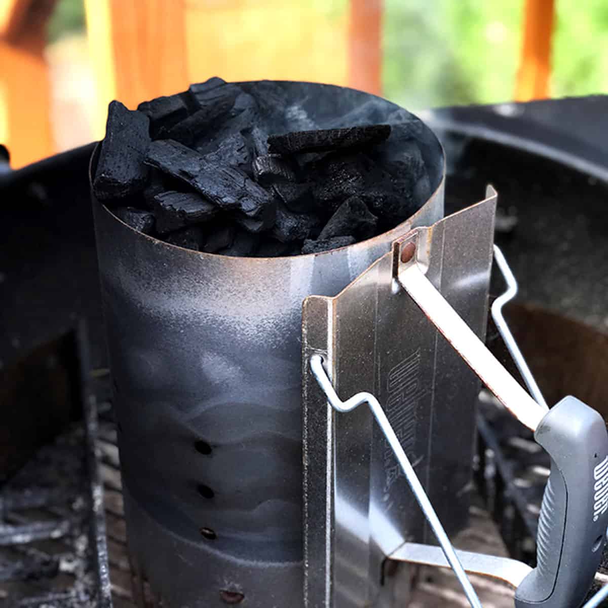 a charcoal chimney that has just been lit, sitting in a grill.