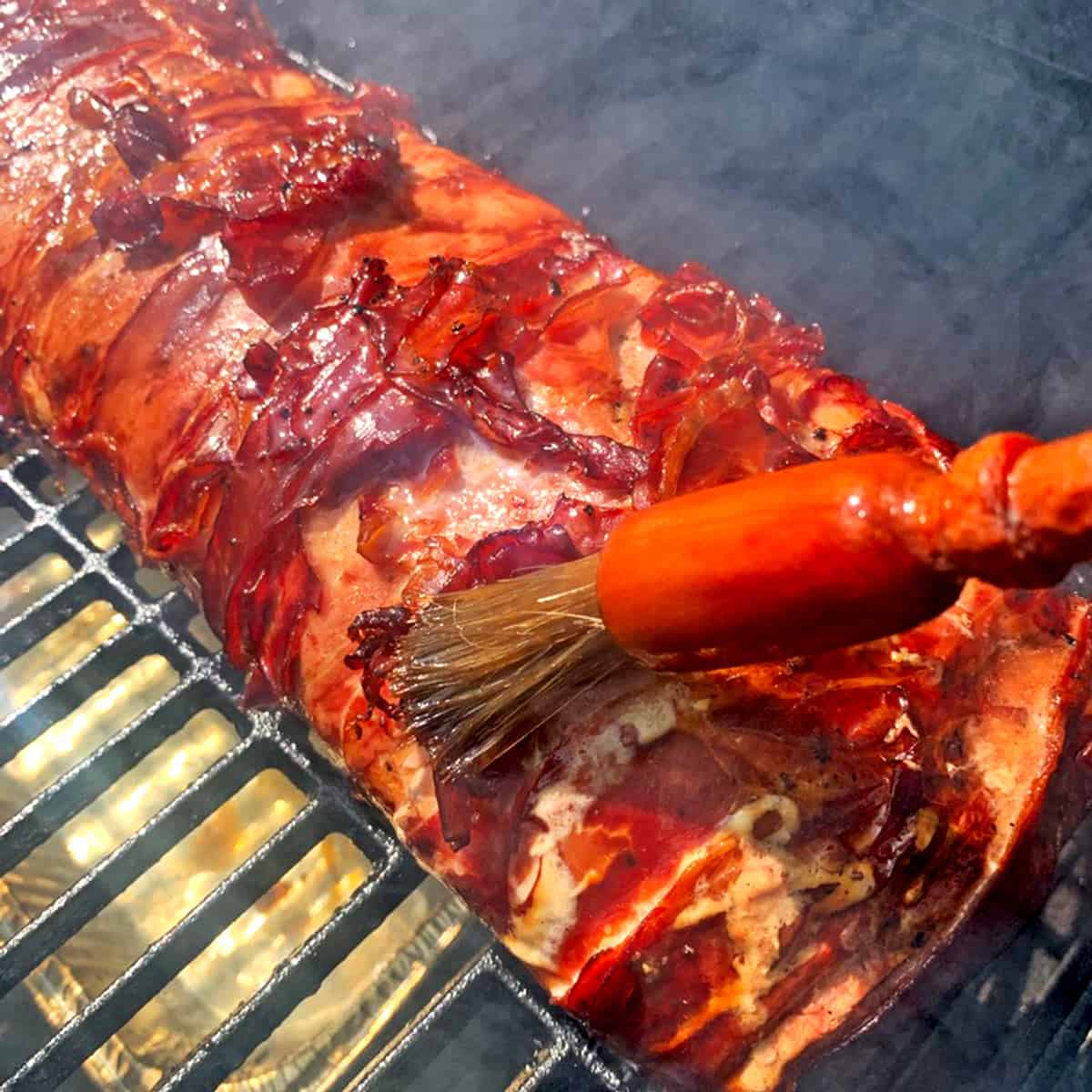 Brushing juice on a piece of meat on the grill.