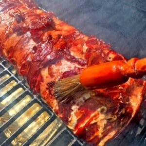 Brushing sauce on a piece of meat on a grill.r.