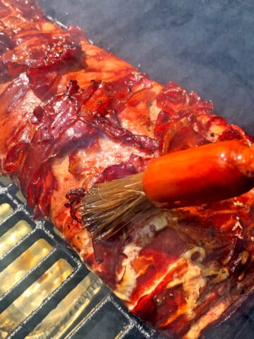 Brushing sauce on a piece of meat on a grill.r.