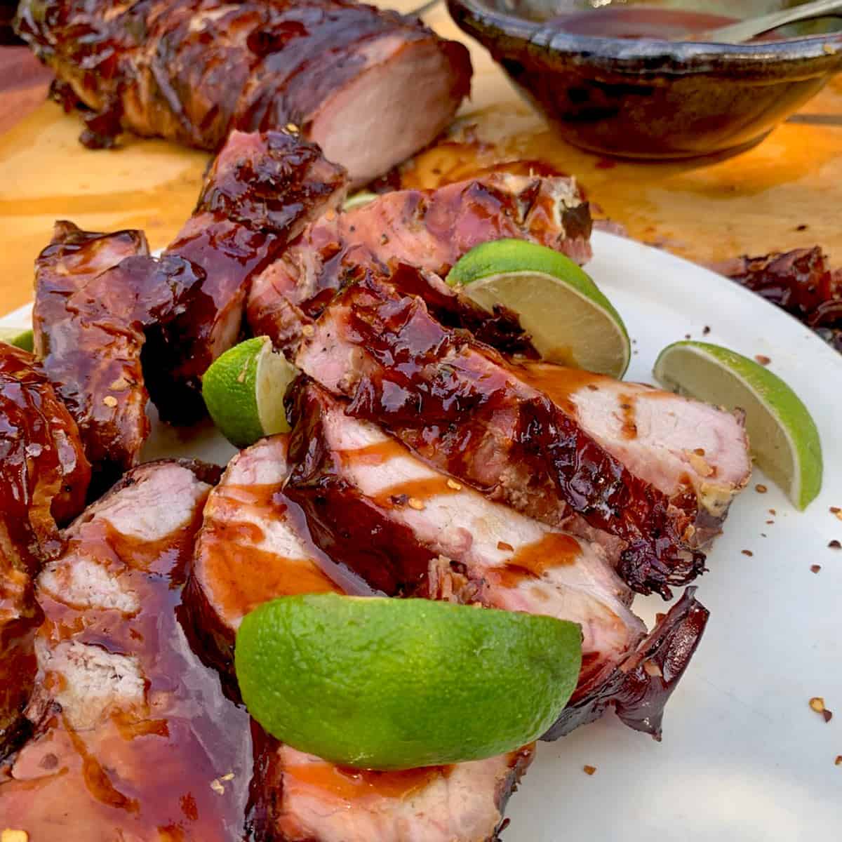 A plate of meat with lime wedges.