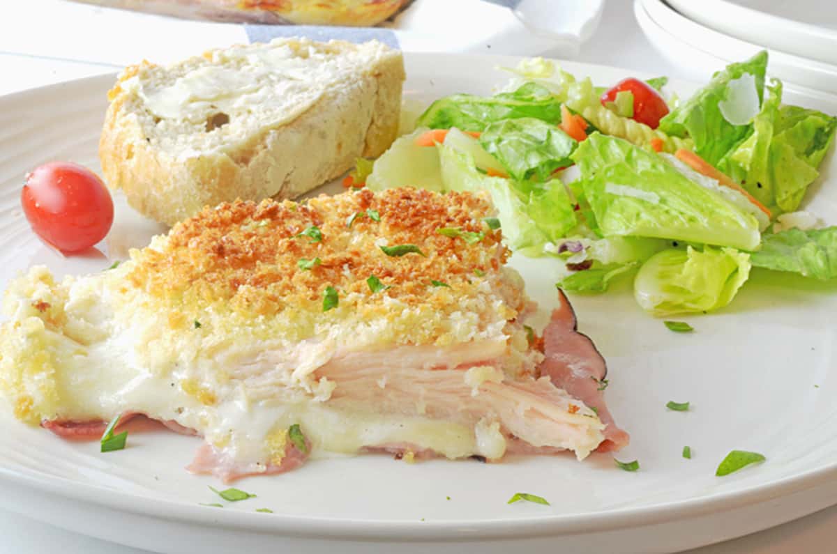 A serving of chicken cordon bleu casserole with salad and bread.