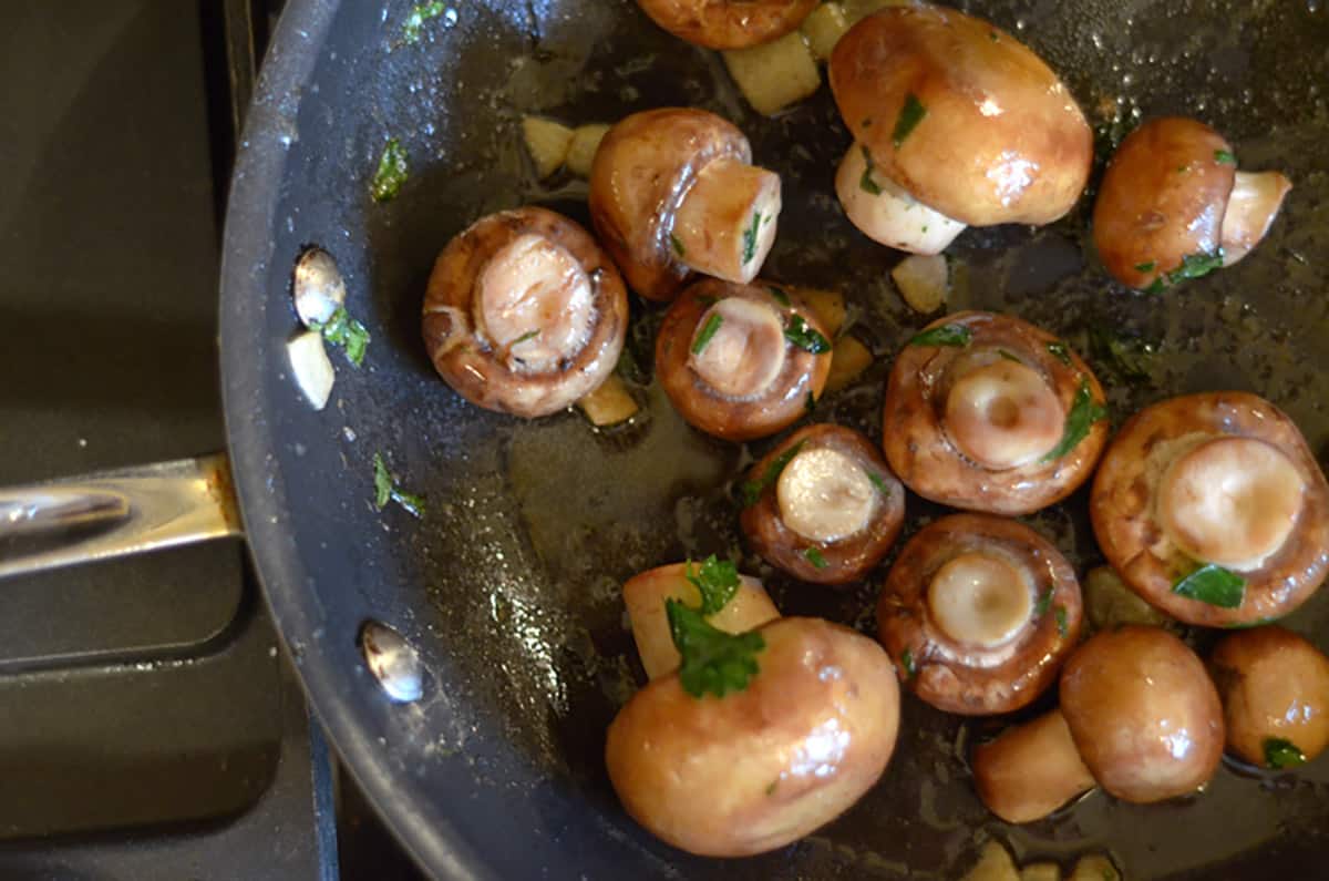 A pan of mushrooms being sauteed.