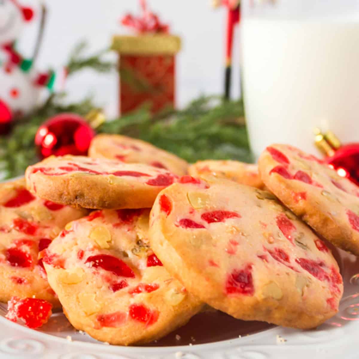 A plate of cherry Christmas cookies and a glass of milk.