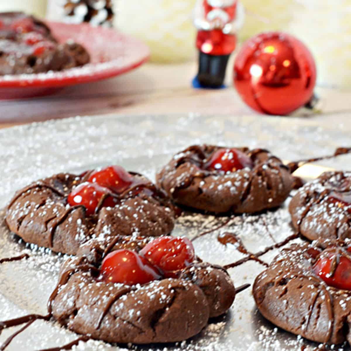 A group of chocolate cookies topped with cherries.