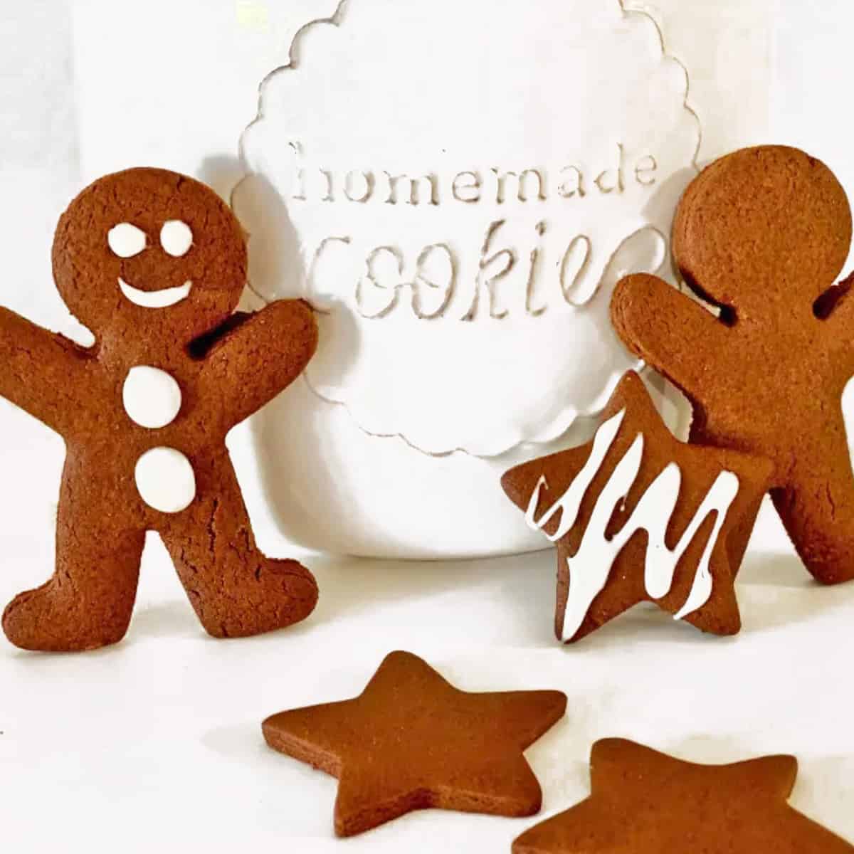 Some gingerbread cookies standing up next to a cookie jar.