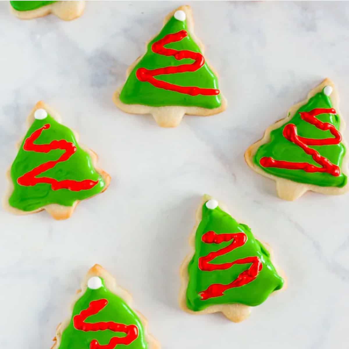 A group of Christmas cookies shaped like Christmas tress with green royal icing.