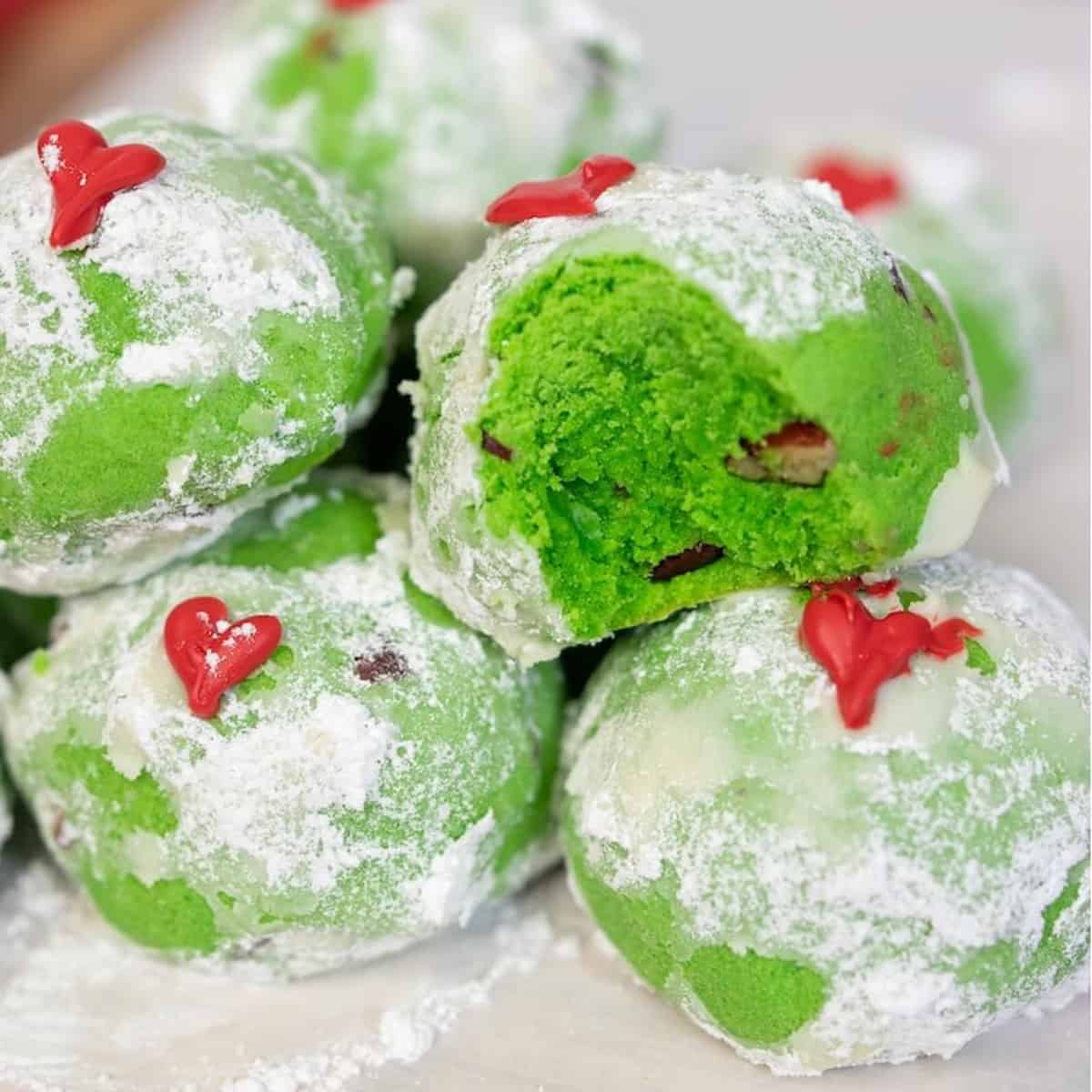 A pile of round green cookies with a dusting of powdered sugar on them.