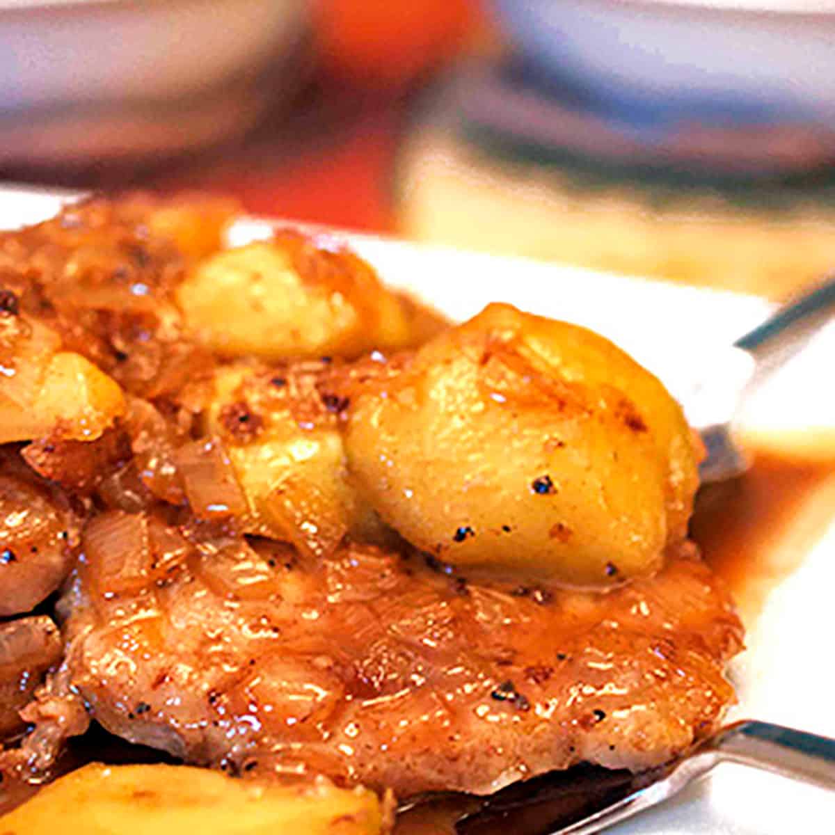 A cooked pork chop with a slice of apple.